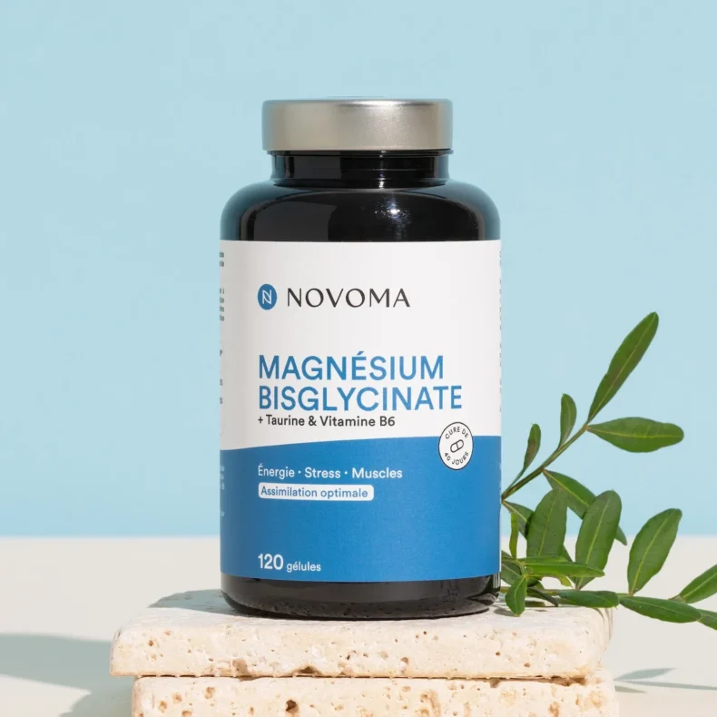Flacon de Magnésium Bisglycinate Novoma 120 gélules posé sur des pierres, branche d'olivier sur fond bleu